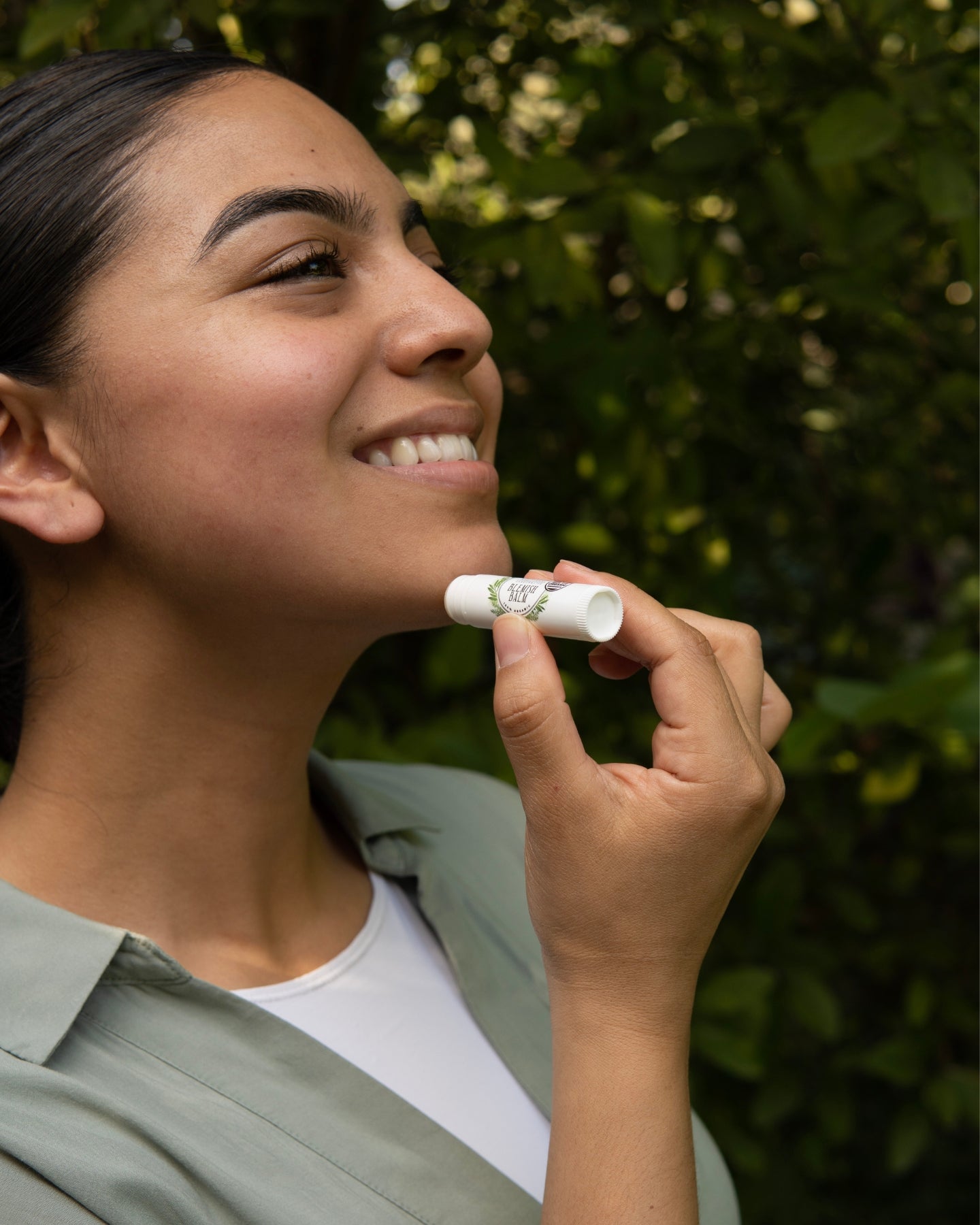 A smiling woman applies the Blemish Balm on her chin.